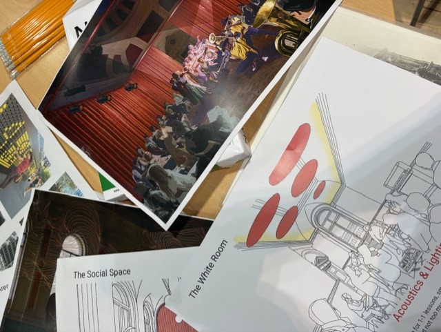 Documents on a table with architectural images and examples of brightly coloured and interactive art work outside buildings